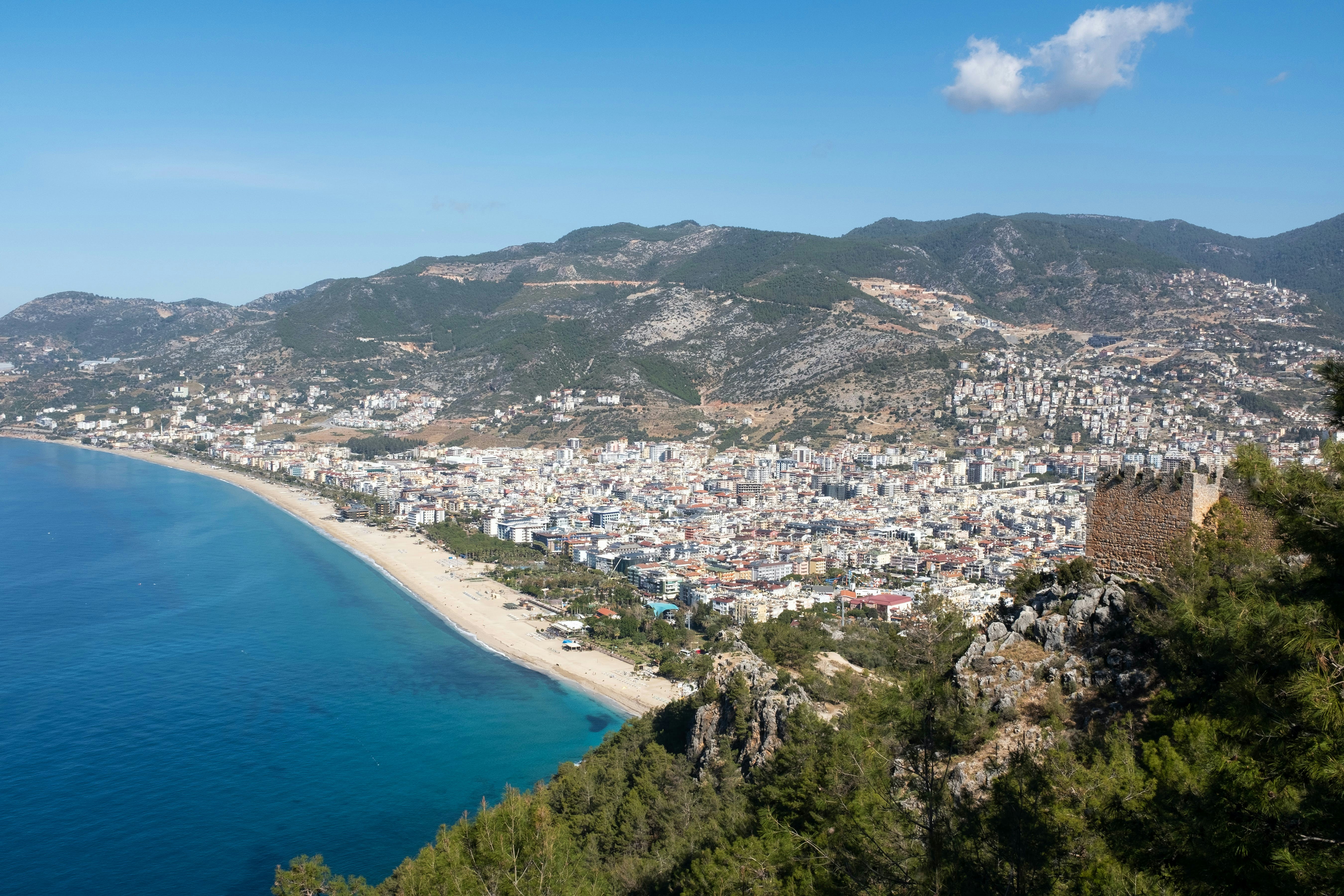 Aerial view of Alanya beach and city from the hilltop castle, with the Mediterranean and mountains beyond