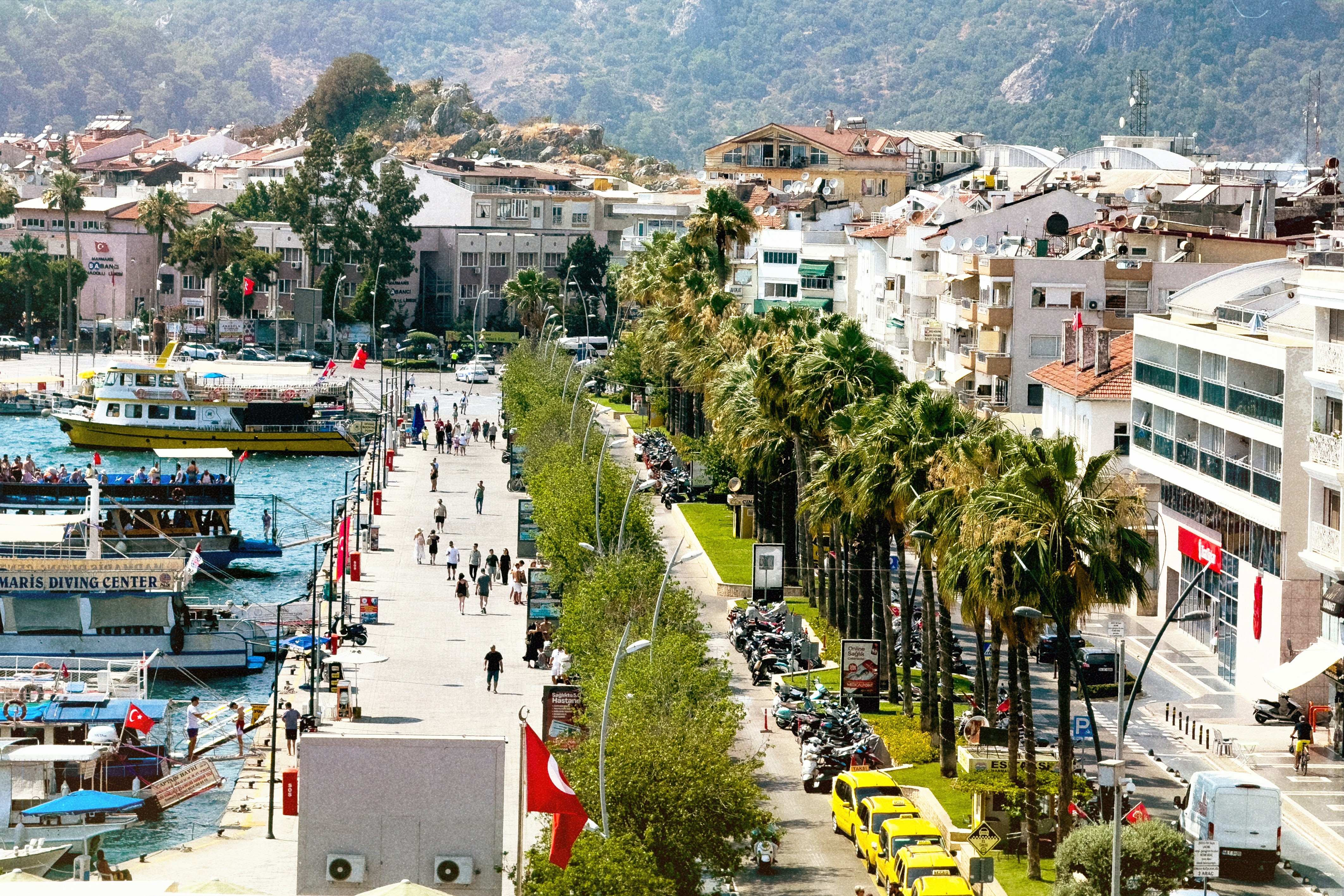Marmaris marina waterfront with boats, Turkish flags and palm promenade, Muğla, Turkey