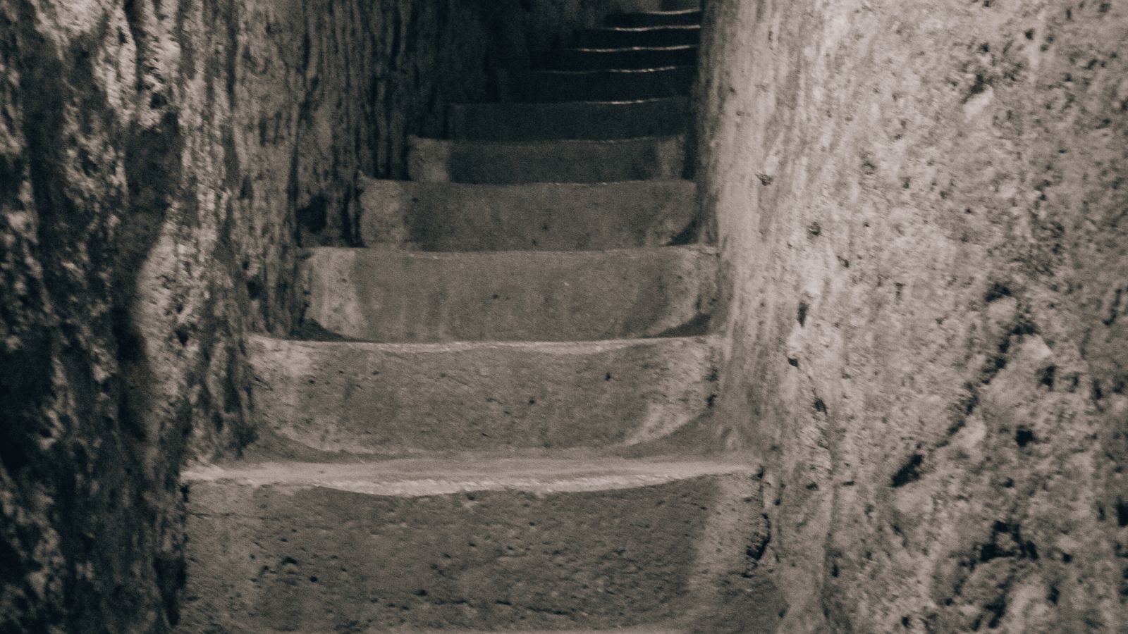 Ausgetretene, in den Stein gehauene Treppe, die durch einen engen Tunnel in der unterirdischen Stadt Derinkuyu aufsteigt