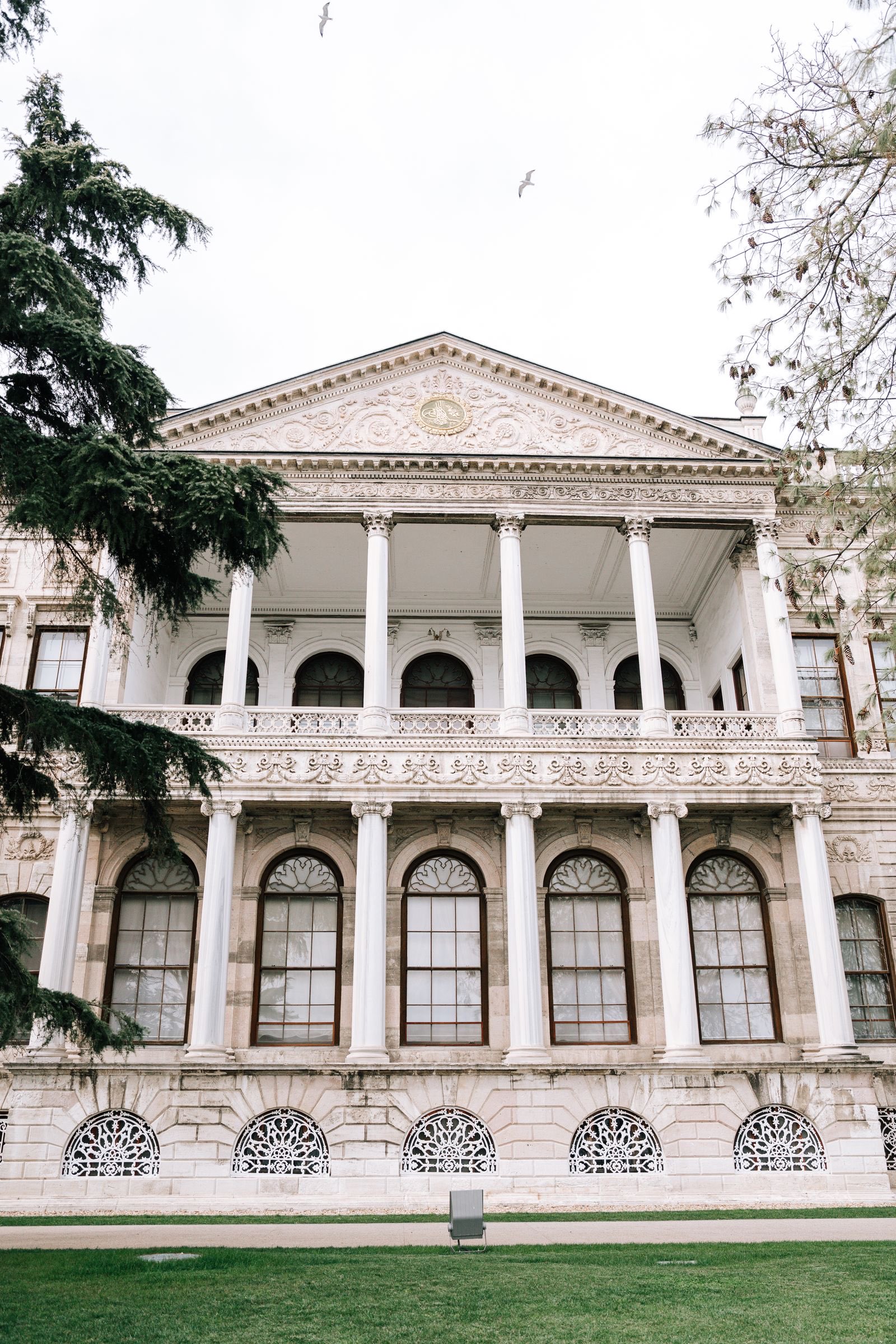 Neoklassizistische Palastfassade mit weißen Marmorsäulen, Rundbogenfenstern und Giebel, vom Garten aus gesehen, Dolmabahçe-Palast, Istanbul