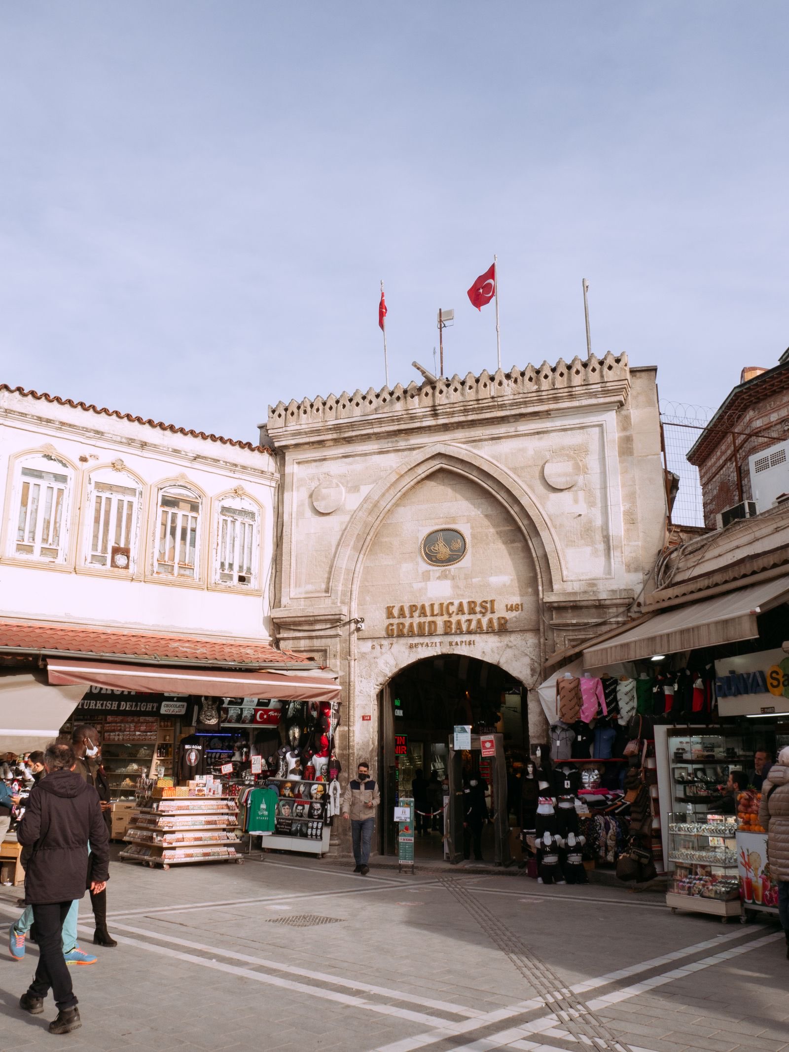 Das Beyazıt-Tor des Großen Basars mit Kapalıçarşı-Schriftzug, türkischen Flaggen und Geschäften davor, Istanbul