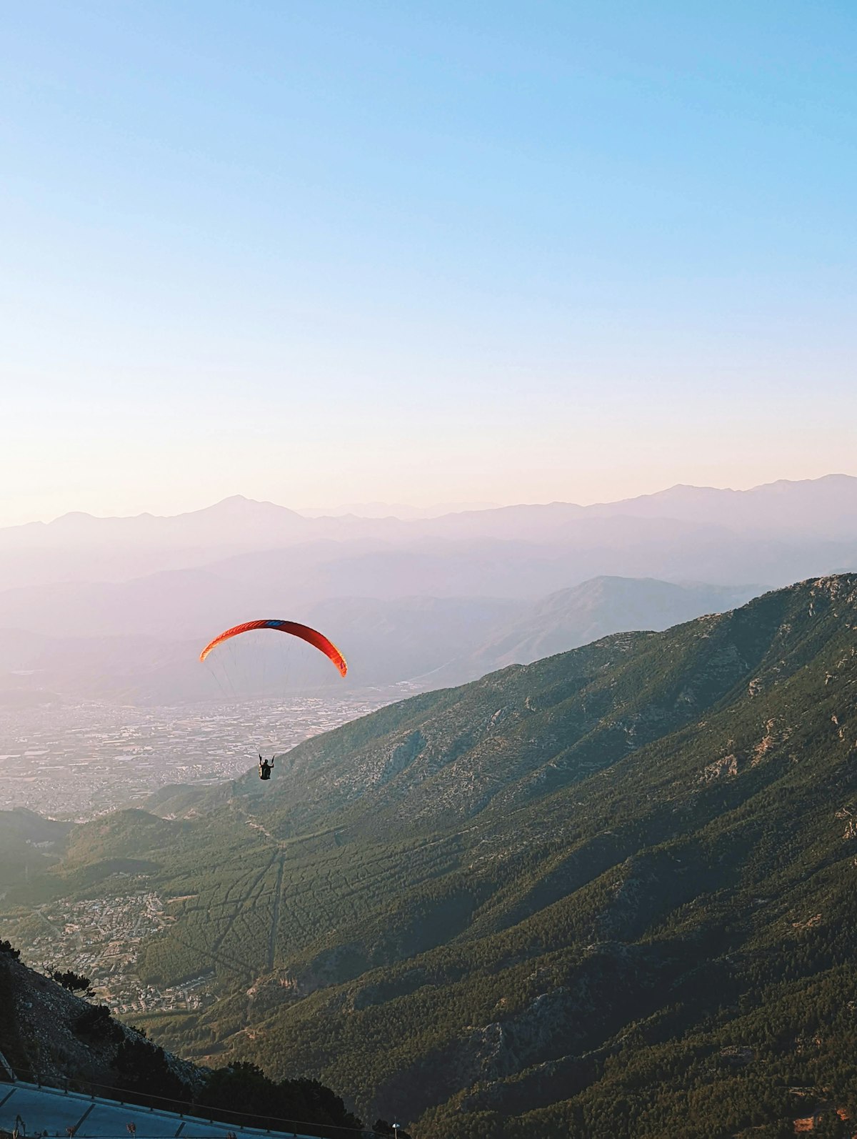 Paraglider soaring from Babadağ mountain over the green valley near Ölüdeniz, Turkey