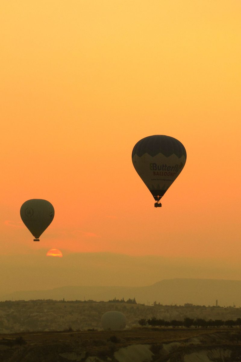 Hot air balloons over Cappadocia beneath an orange sunset