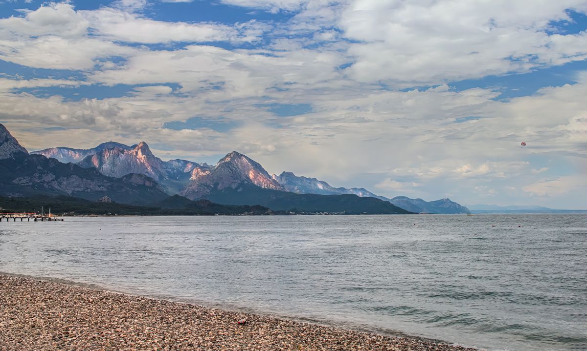 Kemer coastline with pebble beach and Taurus Mountains backdrop, Antalya, Turkey
