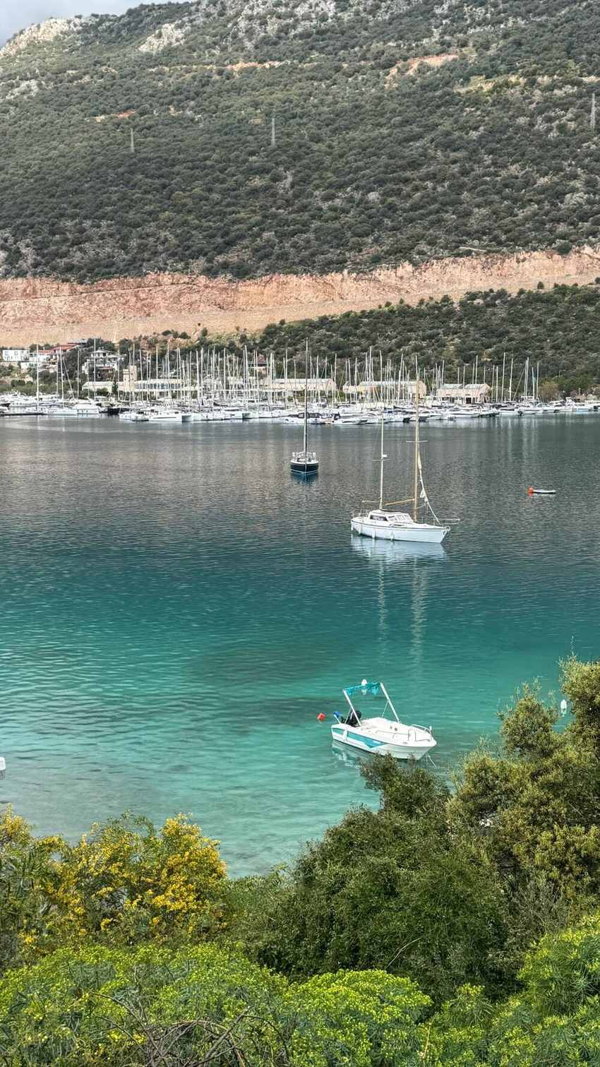 Port de Kaş avec bateaux de plongée et toits blancs de Kalkan en terrasses face à la mer Méditerranée