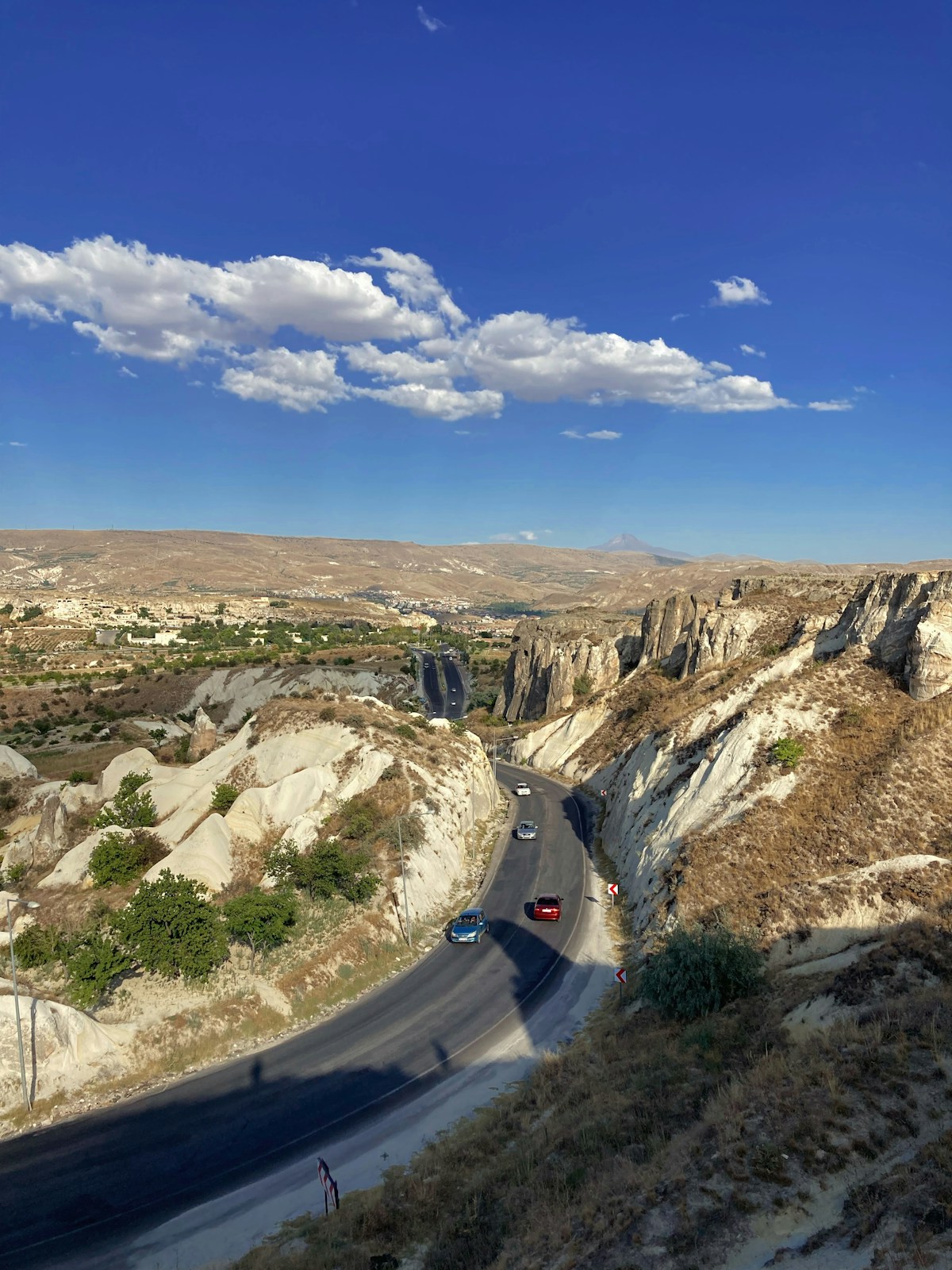Cars driving along a winding road through the rocky Cappadocian landscape near Nevşehir, Turkey