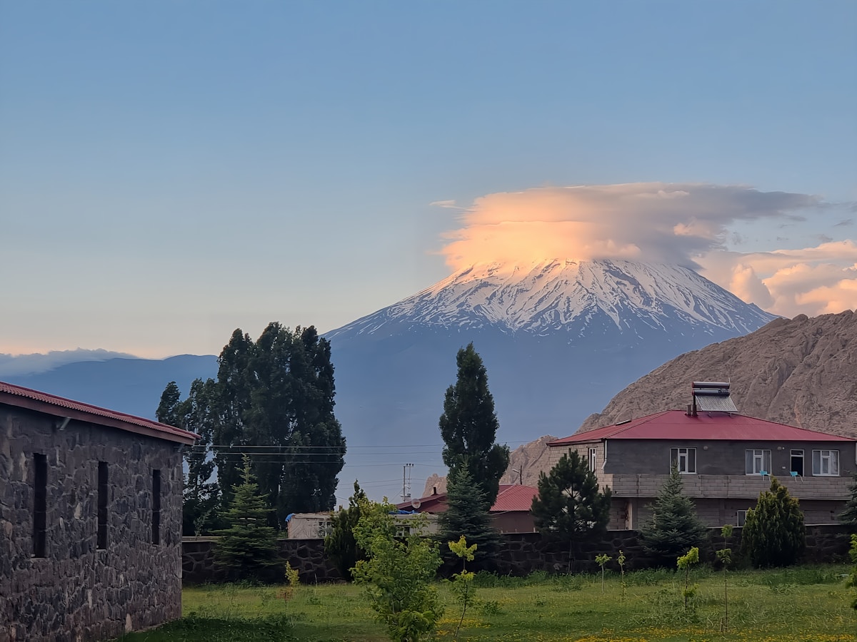 Snow-capped Mount Ararat at sunset with a lenticular cloud over the summit, houses and trees in the foreground, Doğubayazıt, Ağrı, Turkey