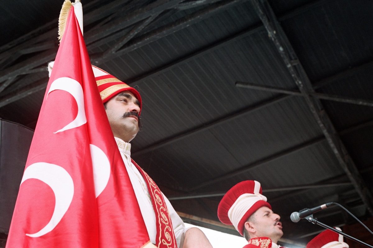Performers in traditional Ottoman ceremonial dress holding the Turkish crescent flag at a cultural event in Istanbul