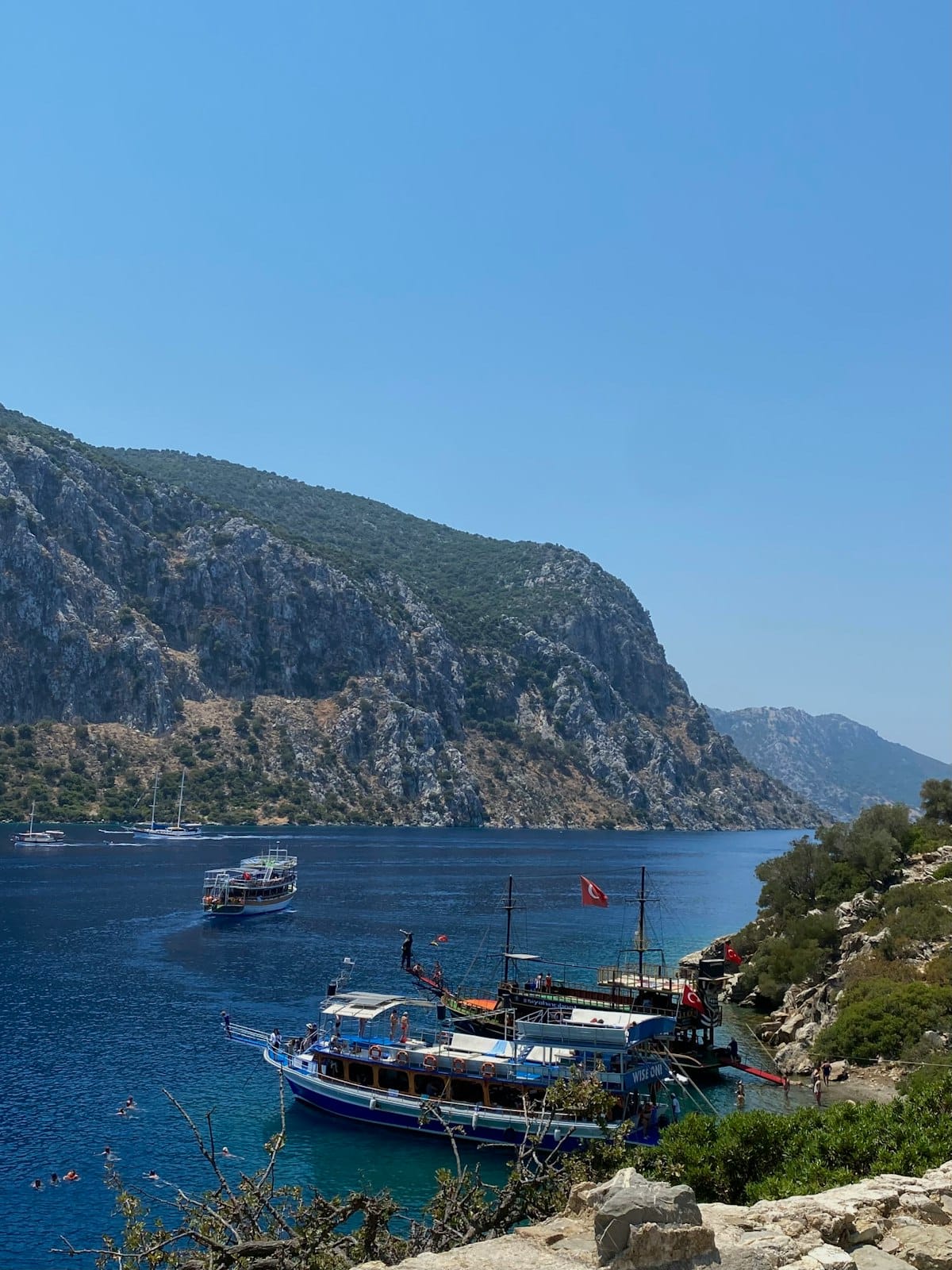 Turkish tour boats anchored in a bay near Marmaris, surrounded by steep pine-forested cliffs