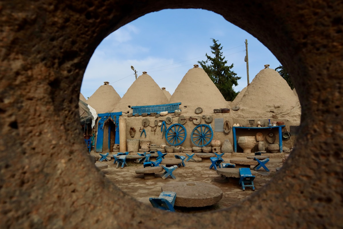 Conical mud-brick beehive houses framed through a circular stone portal at Harran, Şanlıurfa, southeastern Turkey
