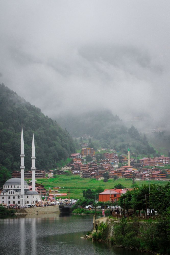 Nebel über Holzhäusern und einer weißen Moschee am See von Uzungöl