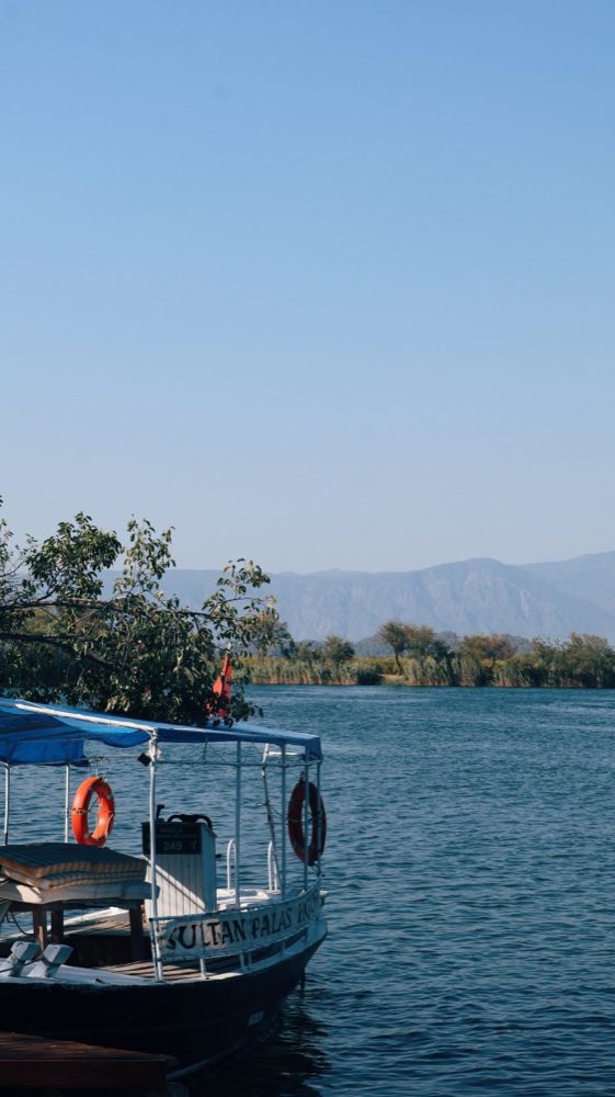 Bateau en bois amarré sur la rivière calme de Dalyan avec des montagnes au loin