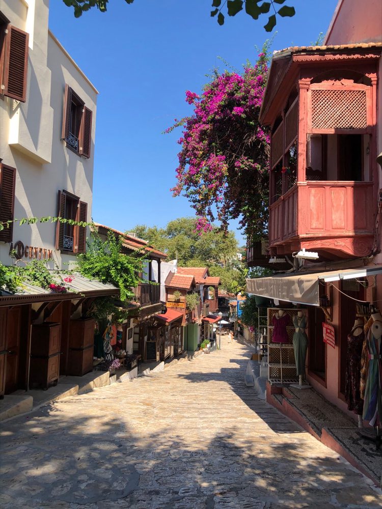 Ruelle pavée de la vieille ville de Kaş avec bougainvillées et balcon ottoman en bois