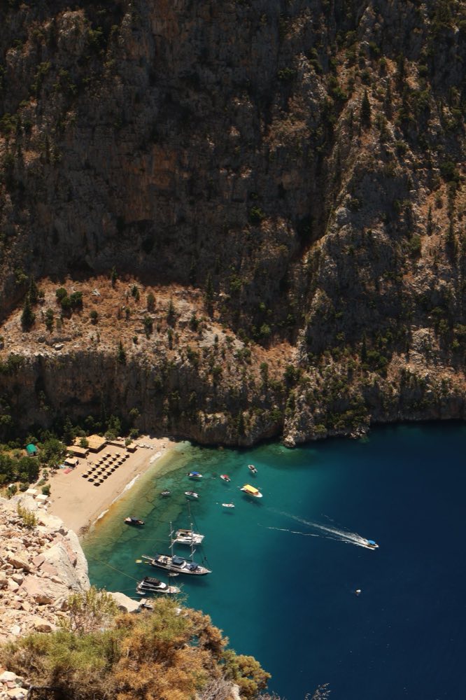Plage et bateaux de la vallée des Papillons au pied de falaises abruptes près de Faralya