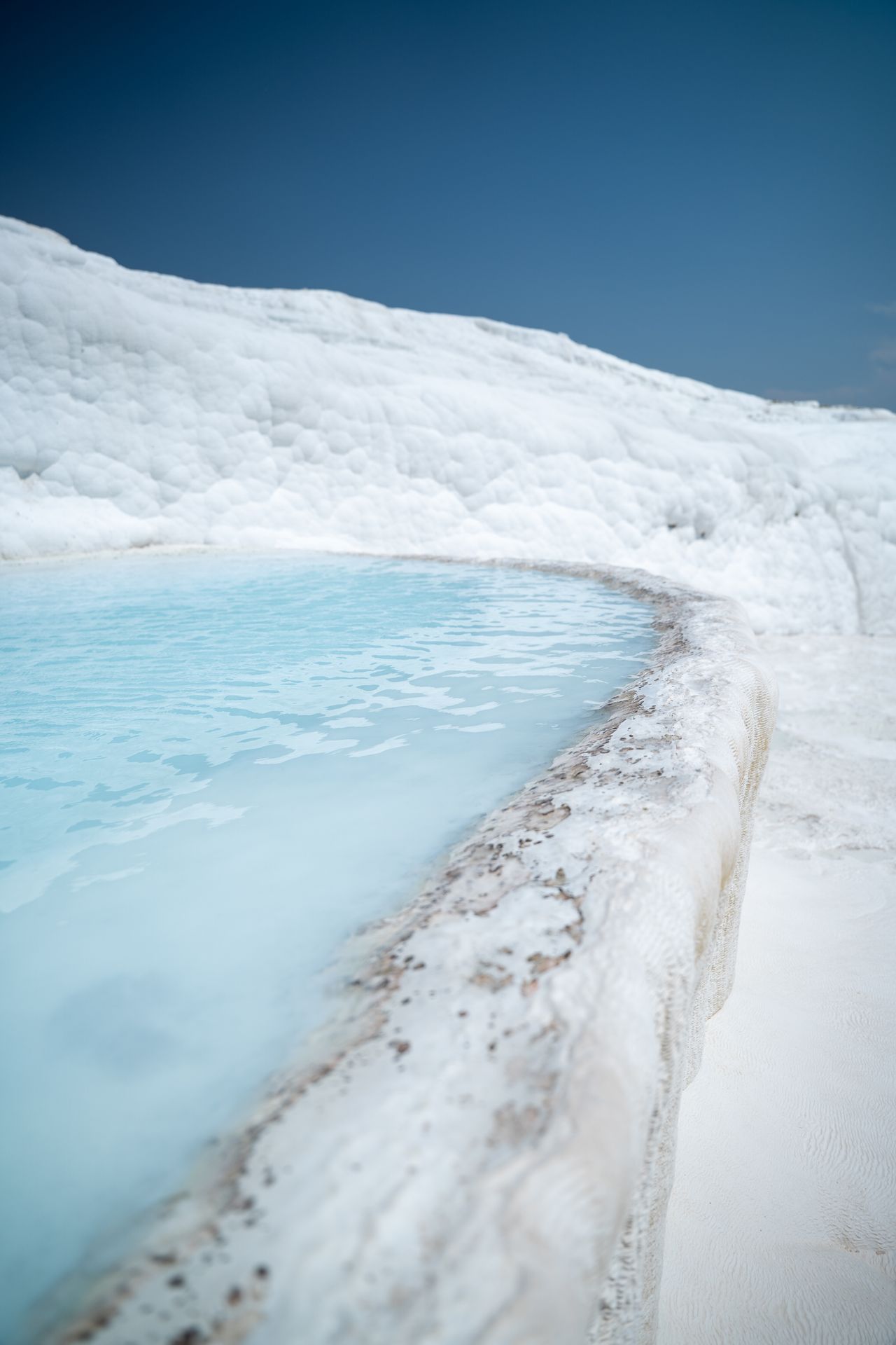 Eau thermale turquoise laiteuse dans une vasque de travertin blanc à Pamukkale