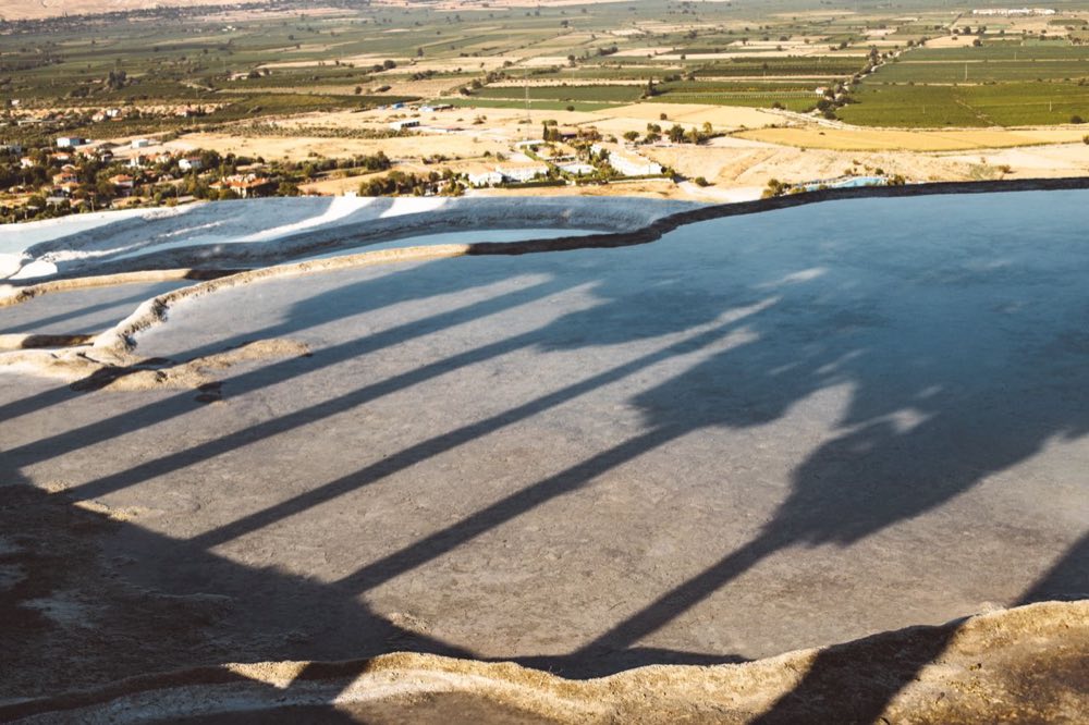 Vue en lumière dorée sur les terrasses de travertin de Pamukkale et la vallée en contrebas