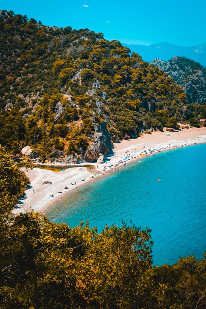 Der Strand von Olympos schwingt sich am türkisfarbenen Wasser unterhalb kiefernbewachsener Taurushänge entlang