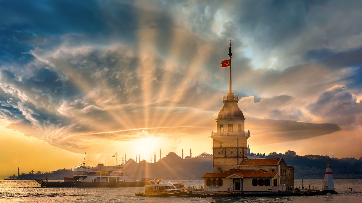 Kız Kulesi (Maiden's Tower) rising from the Bosphorus at sunset with the Istanbul skyline and mosque silhouettes behind
