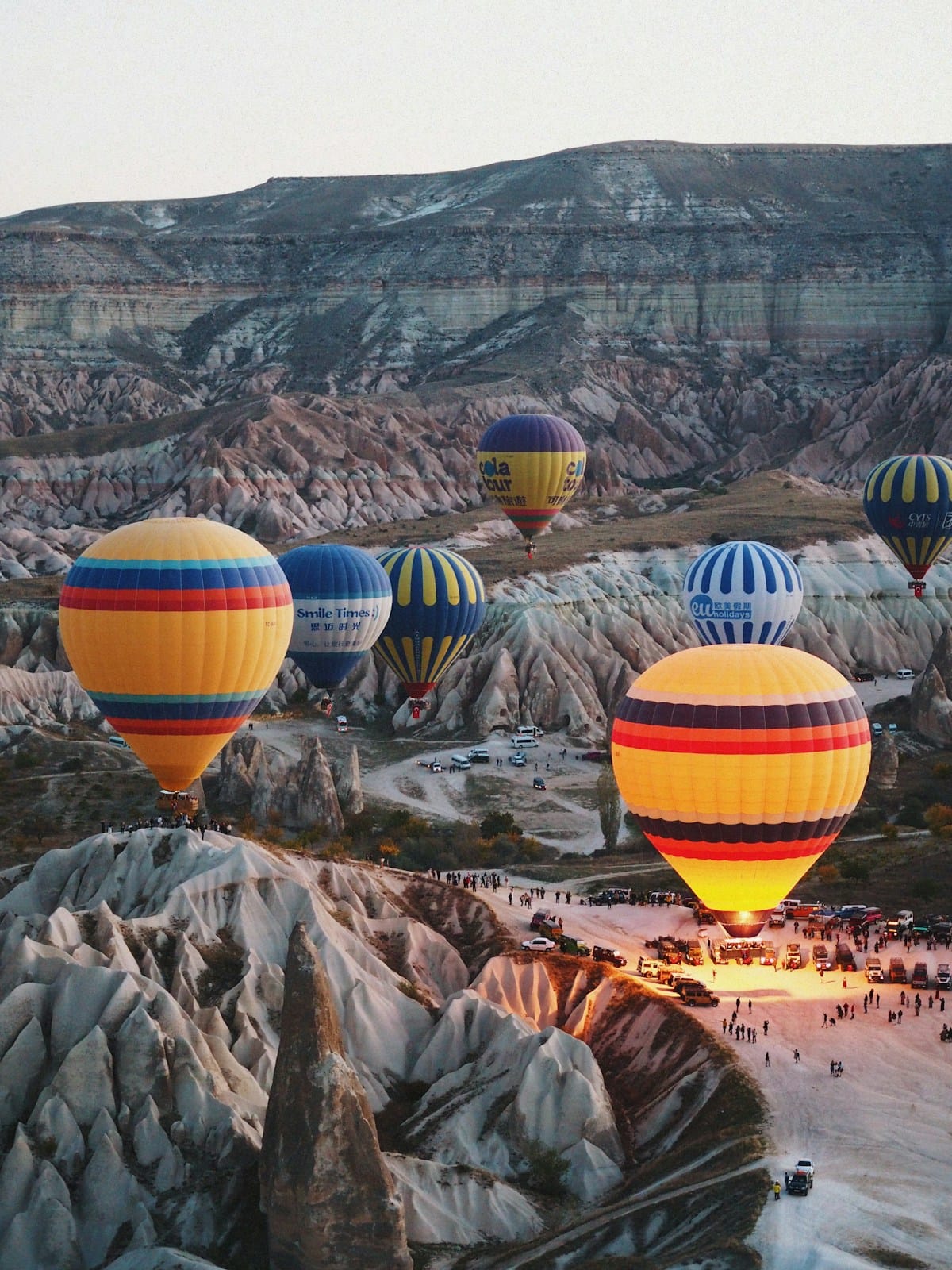 Colourful hot air balloons lifting off at dawn over the fairy chimney landscape of Göreme, Cappadocia, Turkey