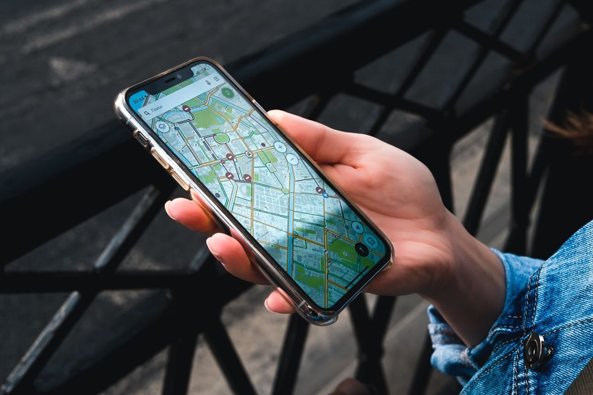 Hand hält ein Smartphone mit einer GPS-Karte