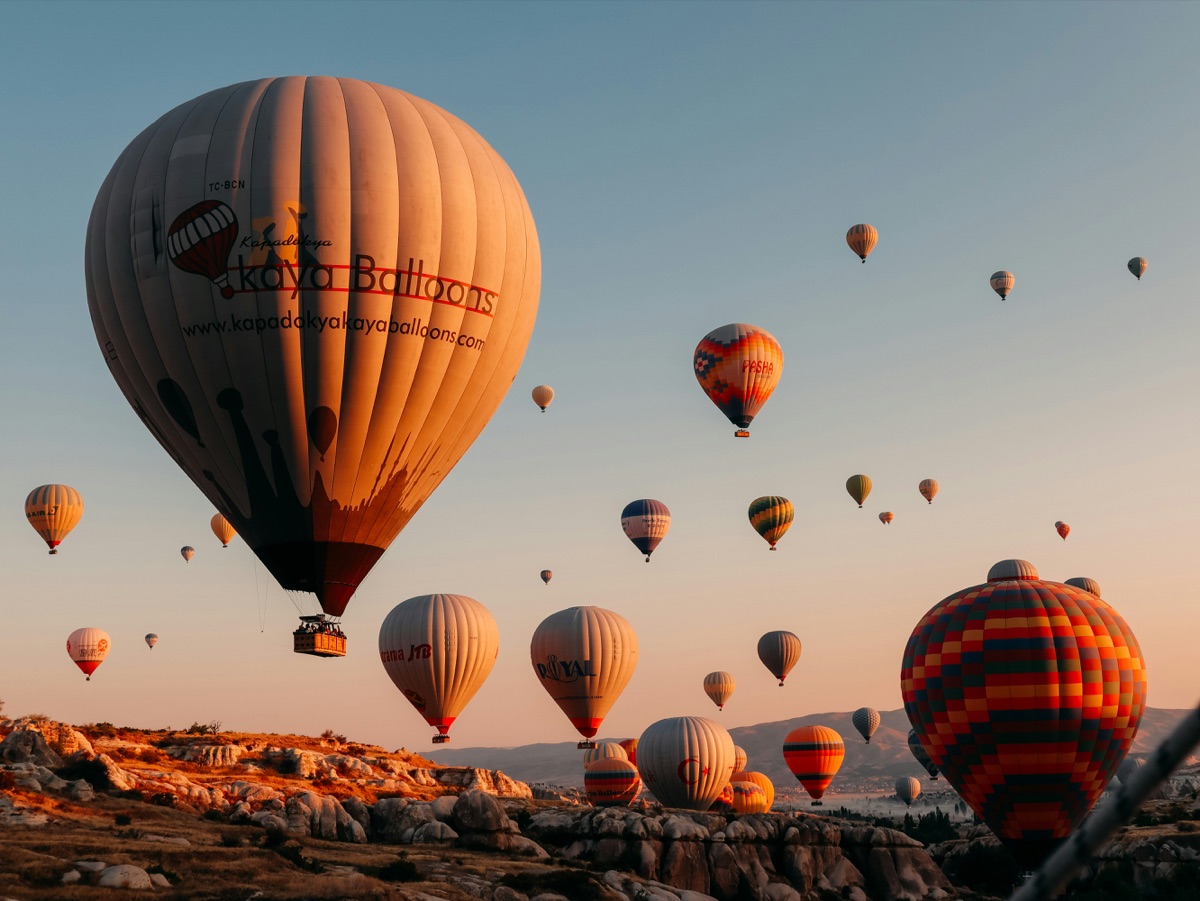 Dozens of hot air balloons over the rocky landscape of Cappadocia at sunrise