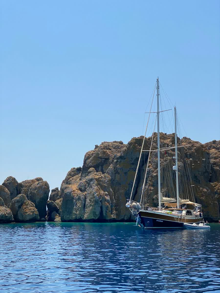 Gulet sailing boat moored beside dramatic rocky cliffs in Marmaris bay, Muğla, Turkey