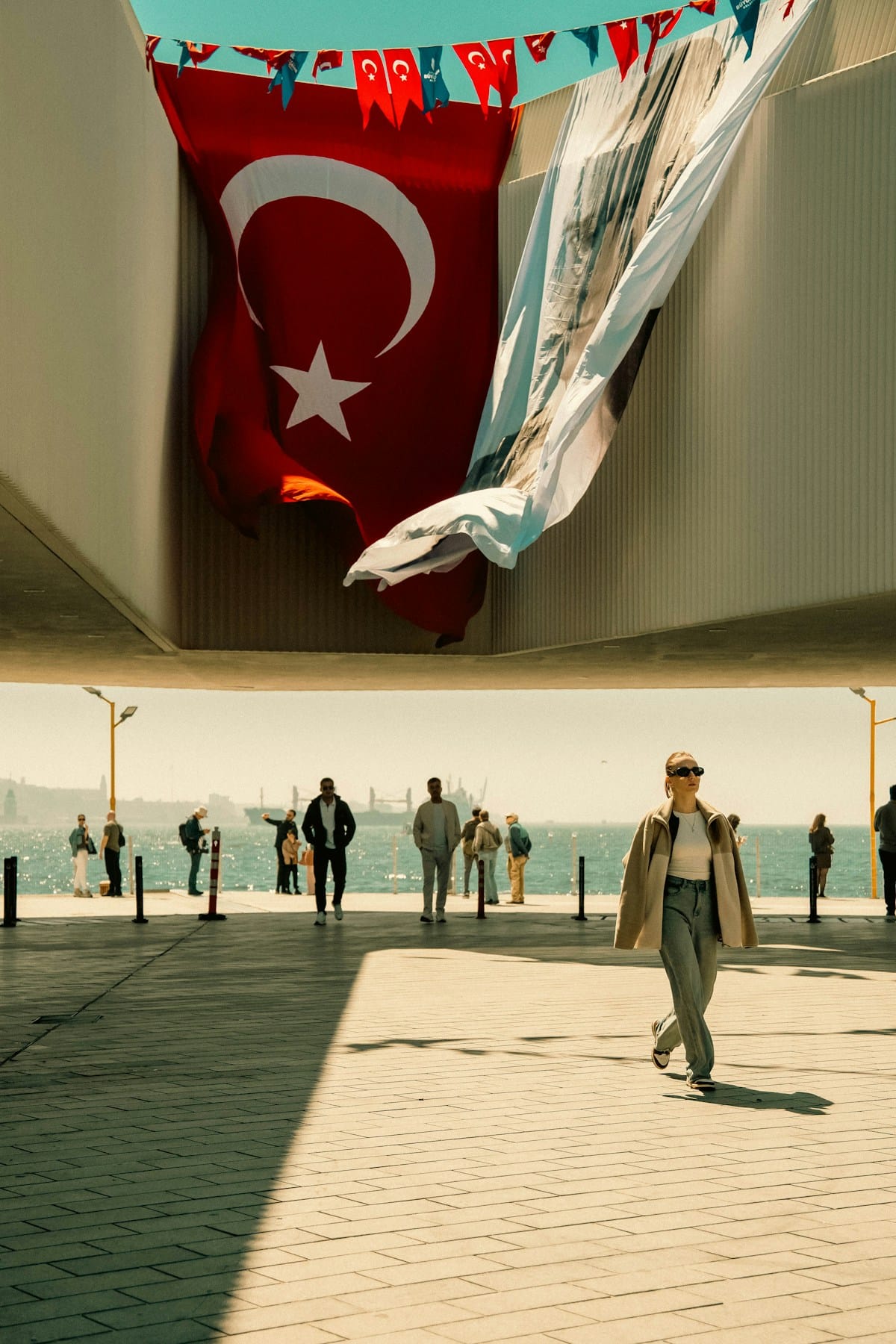 Woman walking confidently under a Turkish flag by the Bosphorus in Istanbul